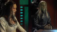 Der Wissenschaftler sitzt mit der Wraith-Königin im großen Konferenzraum von Atlantis.